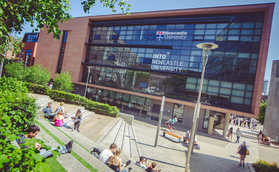 Students sitting outside the INTO Newcastle building. 